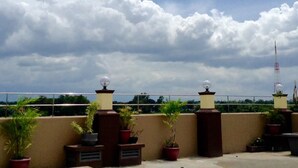 A rooftop terrace with potted plants and a clear view of the sky. - East Square Inn (Bacolod)