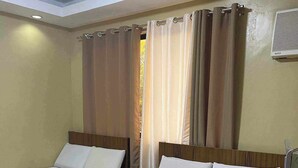 A hotel room with two beds, each with a wooden headboard, white linens, and a rolled towel on the bed. - East Square Inn (Bacolod)