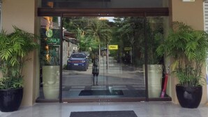 A hotel entrance with a glass door, a 'PULL' sign, and potted plants on either side. - East Square Inn (Bacolod)