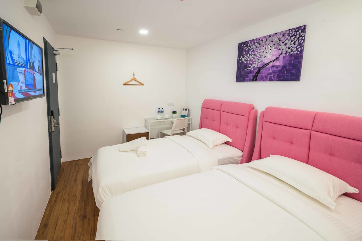 A hotel room with two beds, a desk, a chair, a TV, and a painting on the wall.