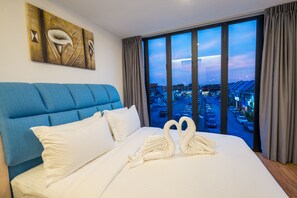 A hotel room with a large bed, a city view through the window, and a painting on the wall. - My Sj Hotel (Subang Jaya)