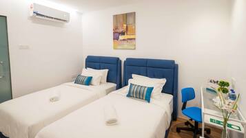 Una habitación de hotel con dos camas, un escritorio, una silla y aire acondicionado.