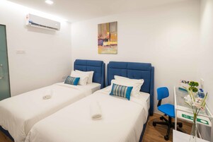 Una habitación de hotel con dos camas, un escritorio, una silla y aire acondicionado.