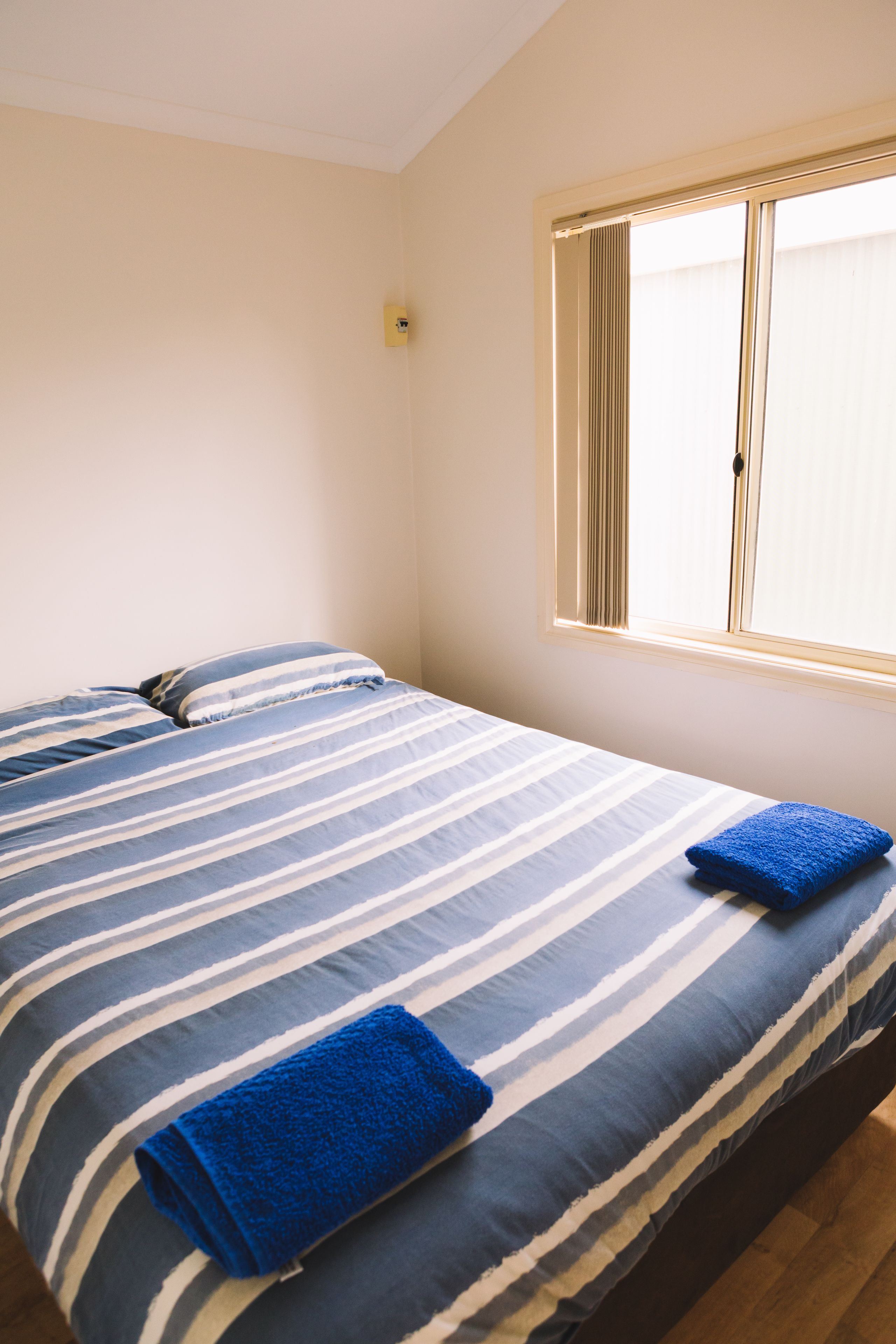 A bedroom with a bed, pillows, and a window.