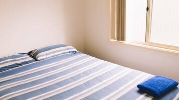 A bedroom with a bed, pillows, and a window.