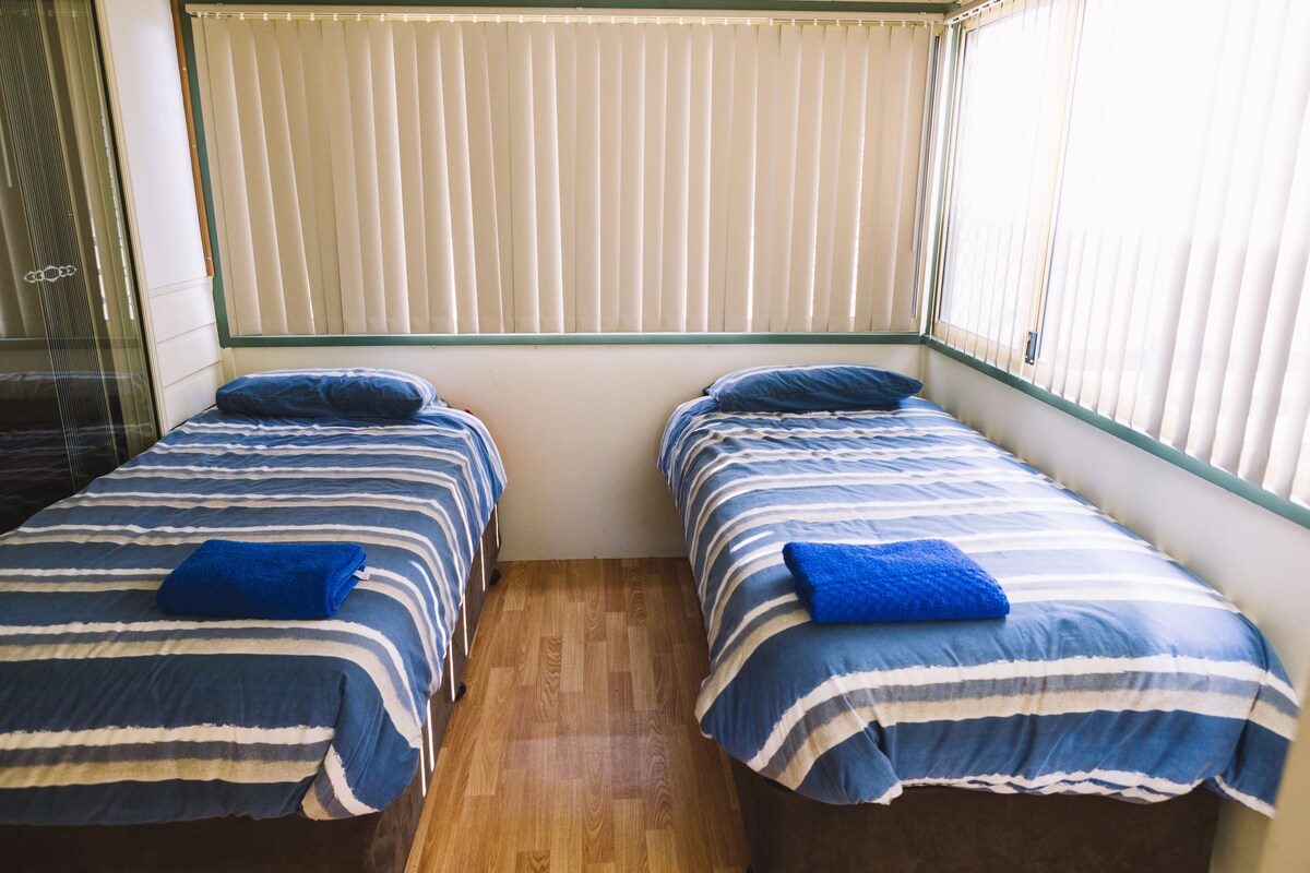 A room with two beds, each with blue and white striped bedding and matching pillows.