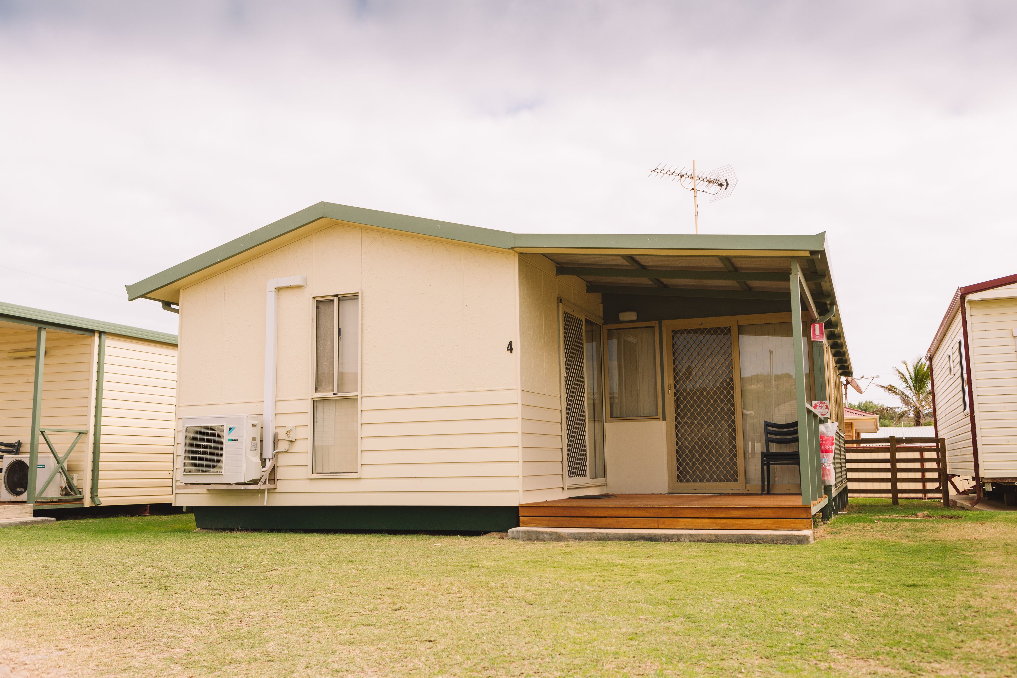 A single-story mobile home with a covered porch, a sliding glass door, and a small deck.