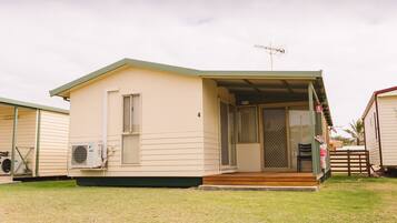 A single-story mobile home with a covered porch, a sliding glass door, and a small deck.