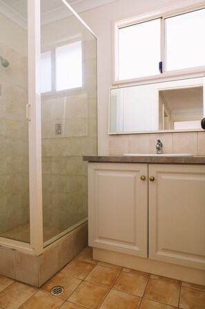 Un baño con ducha, lavamanos y espejo.