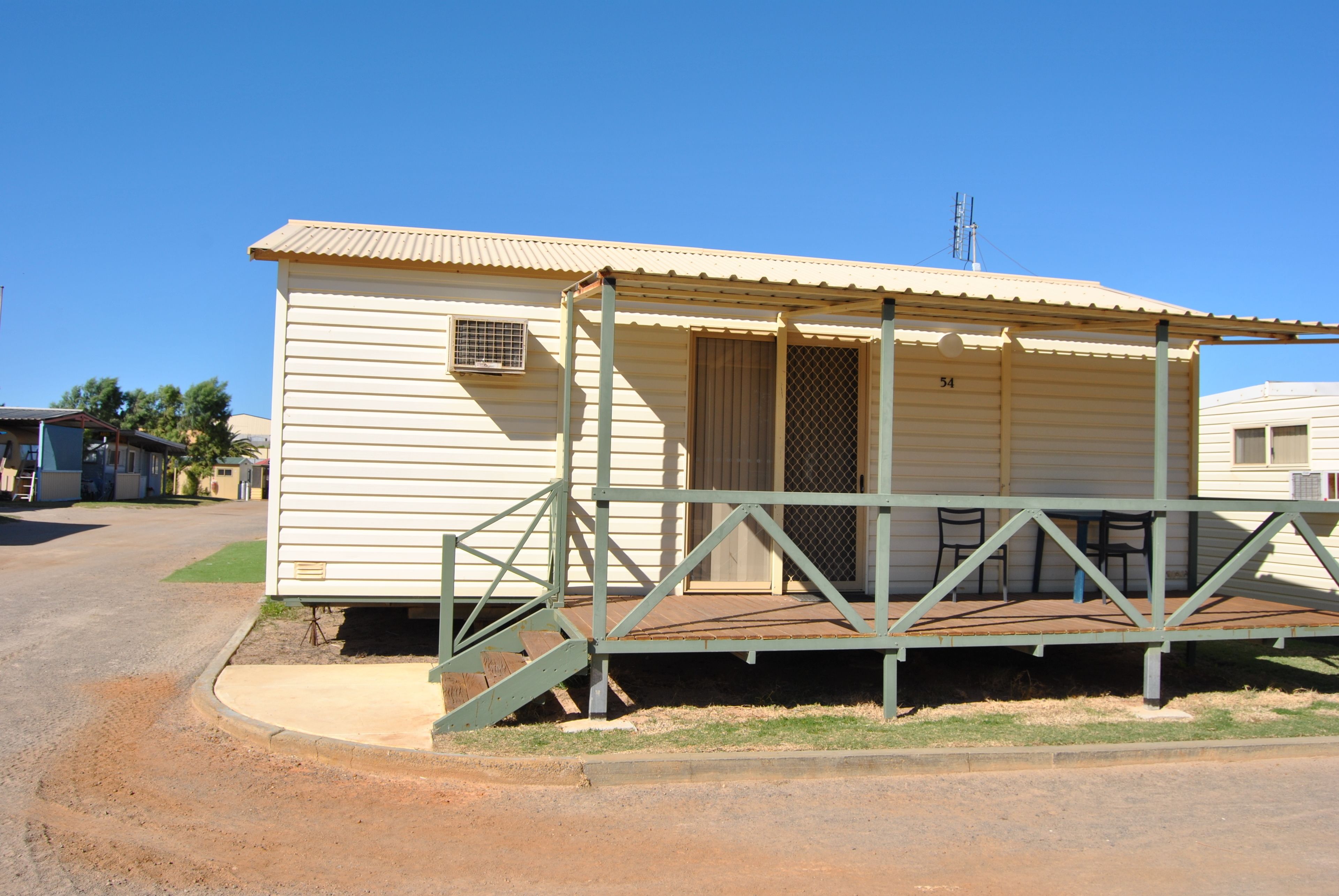A small, single-story mobile home with a porch and a number '54' on the side.