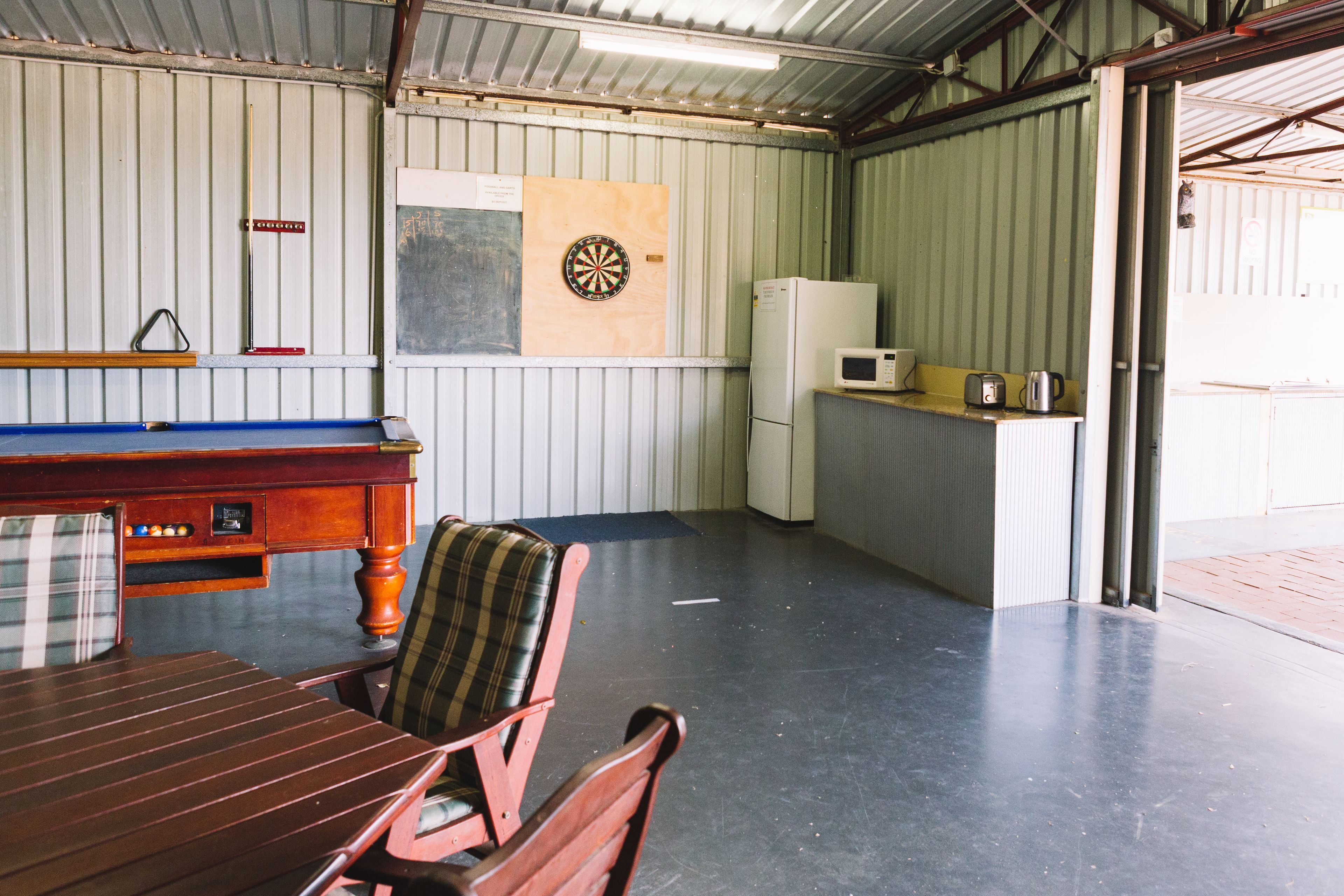 Una habitación pequeña con dardos, microondas y refrigerador.