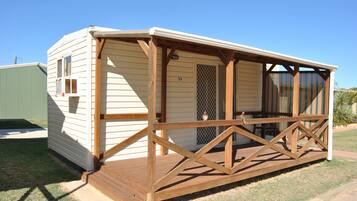 A mobile home with a wooden deck and a screened porch.