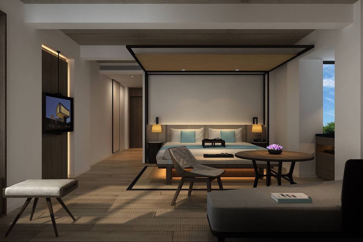 Una habitación de hotel moderna con una cama grande, un escritorio, una silla y una mesita con un jarrón.