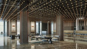 Eine geräumige Lobby mit poliertem Boden, moderner Möblierung und einer Decke mit hängenden Lampen.