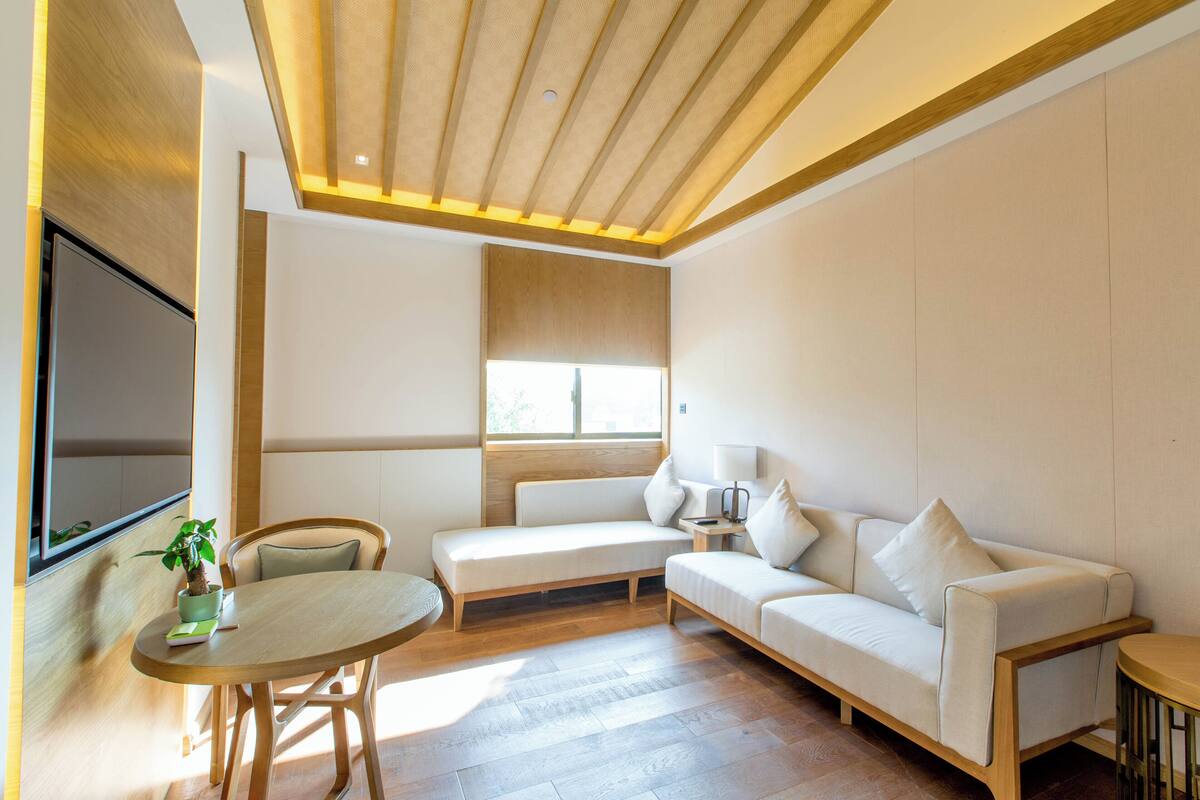 Una sala de estar moderna con un sofá, una mesita y una silla. Se ve una ventana con vistas al exterior.