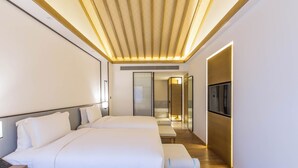 Ein modernes Hotelzimmer mit zwei Betten, einem Fernseher und Holzboden.