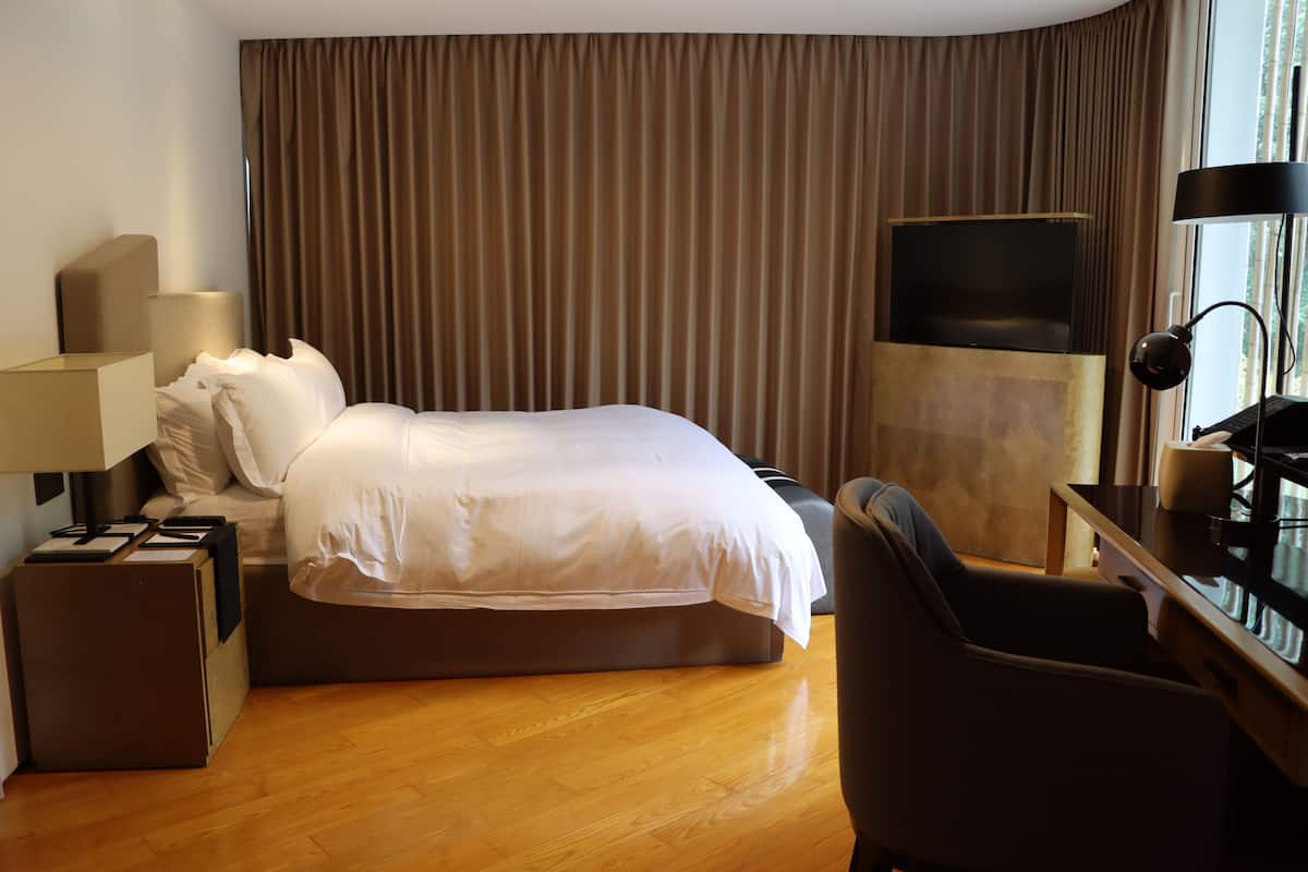 Una habitación de hotel con cama, escritorio, televisor y lámpara.