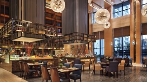 A spacious hotel lobby with a central bar, multiple seating areas, and large windows offering views of the city. - Wanda Realm Huangshi (Huangshi)