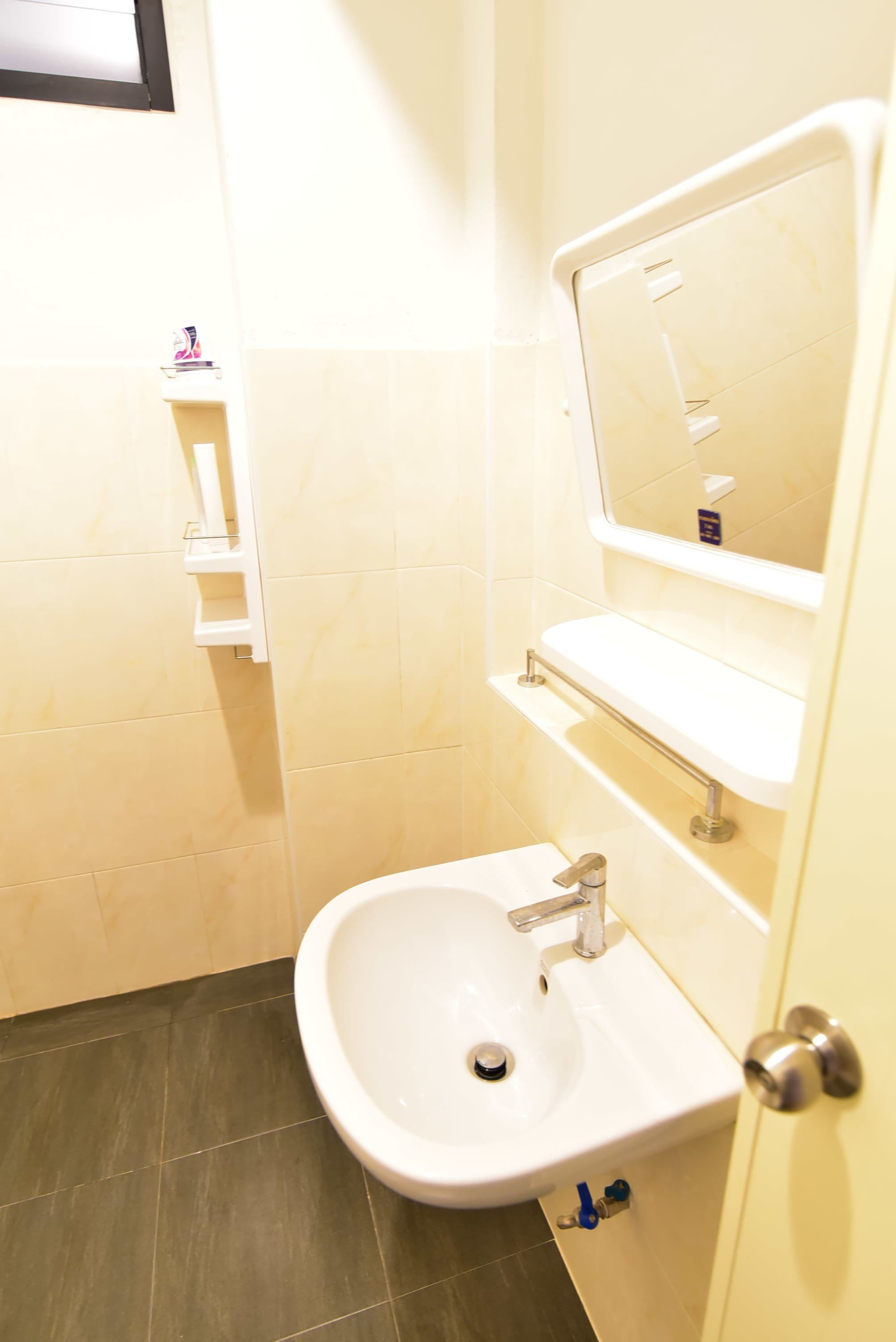 A small bathroom with a white sink, a mirror, and a shelf with toiletries.