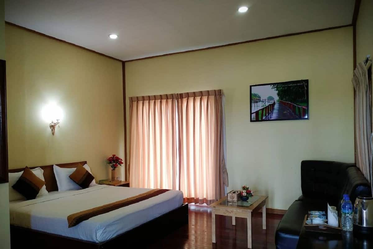 A hotel room with a bed, a small table, a sofa, and a picture on the wall.