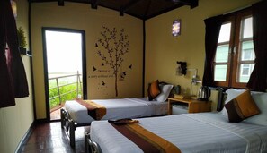A hotel room with two beds, a window with curtains, a wall decal of a tree and birds, and a view of greenery outside. - Moe Yun Gyi Wetlands Resort (Bago)
