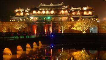 Un bâtiment traditionnel chinois, à plusieurs niveaux, doté d’une architecture riche et ornée, illuminé par une lumière chaleureuse.