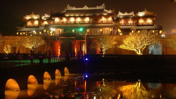 A traditional Chinese building with multiple levels and ornate architecture, illuminated by warm lights.