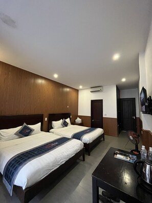A hotel room with two beds, a small table with a kettle, and an air conditioning unit on the wall. - Kha Hotel - Hostel (Hue)