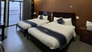 A hotel room with two beds, a balcony, and a view of the city. - Kha Hotel - Hostel (Hue)