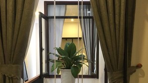A room with a wooden table, a hanging plant, and curtains. - Kha Hotel - Hostel (Hue)