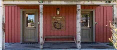 Un bâtiment sur lequel est apposée une enseigne indiquant « MUSTERER’S HUT », et devant lequel se trouve un banc en bois.
