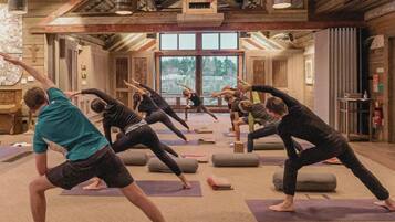 A yoga class in a rustic room with wooden beams and large windows.