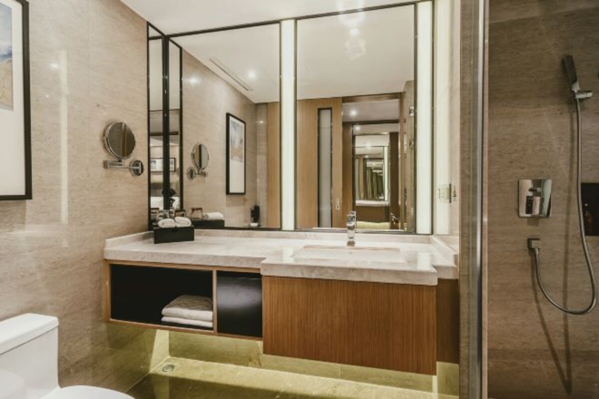 A modern bathroom with a large mirror, a sink, and a shower.