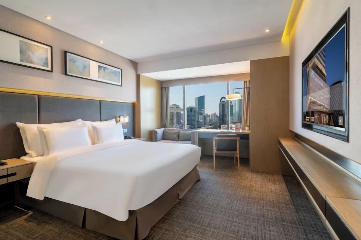 Une chambre d’hôtel avec un grand lit, un bureau et une vue sur la ville.