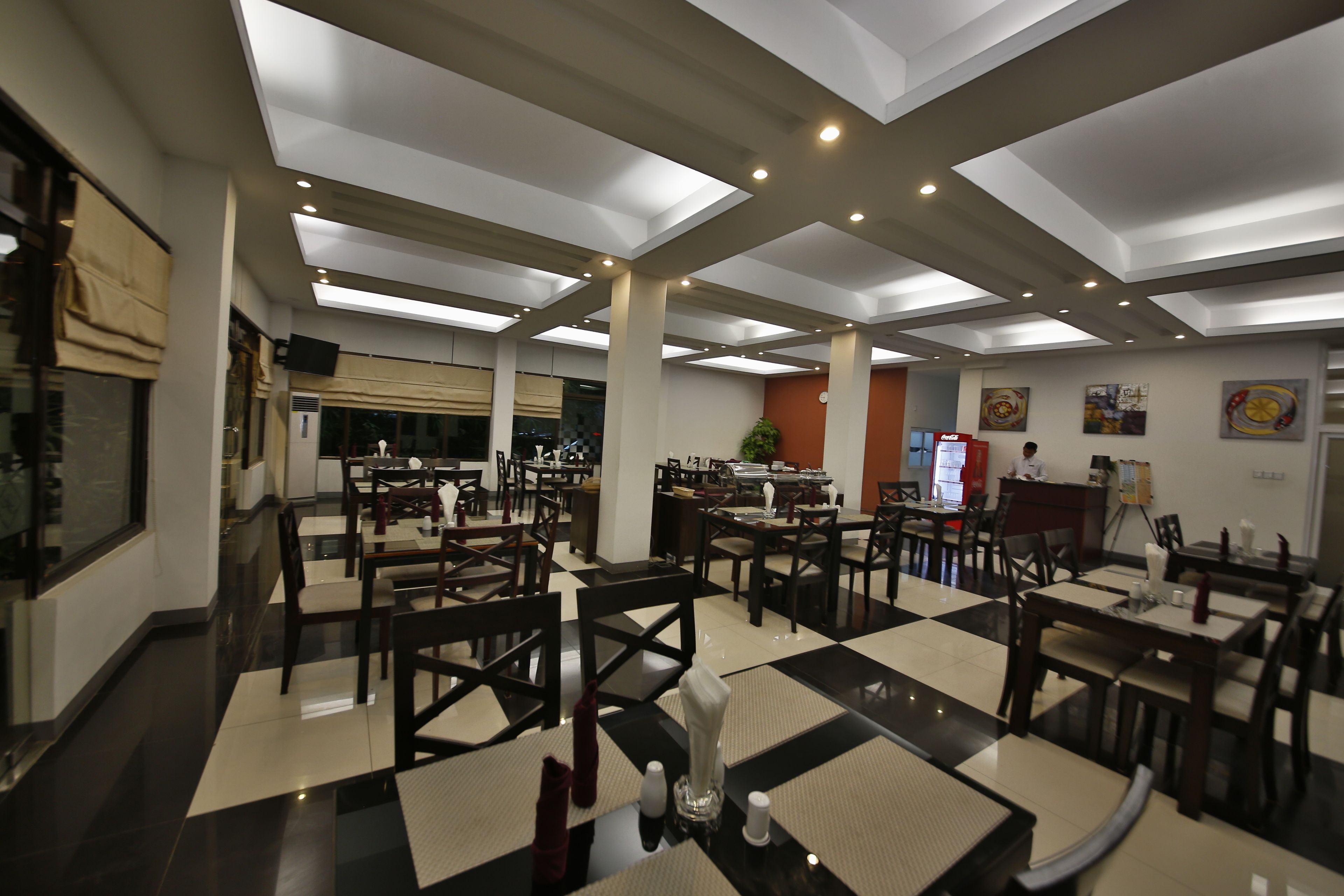 Um restaurante espaçoso com tetos altos, iluminação moderna e padrão de piso xadrez.