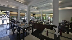 Un restaurante espacioso con techos altos, ventanas grandes y diferentes opciones de asientos, incluyendo mesas y sillas.