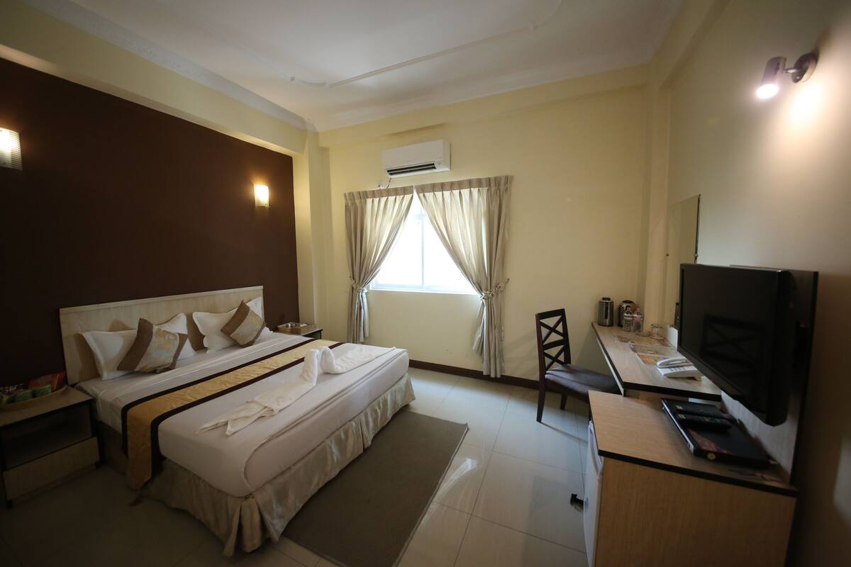 Une chambre d’hôtel équipée d’un lit, d’un bureau, d’une télévision et d’un appareil de climatisation.
