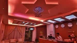 Zona de recepción con diseño de techo en forma de estrella, mostrador de recepción y área de estar con sofás y una mesa de centro.