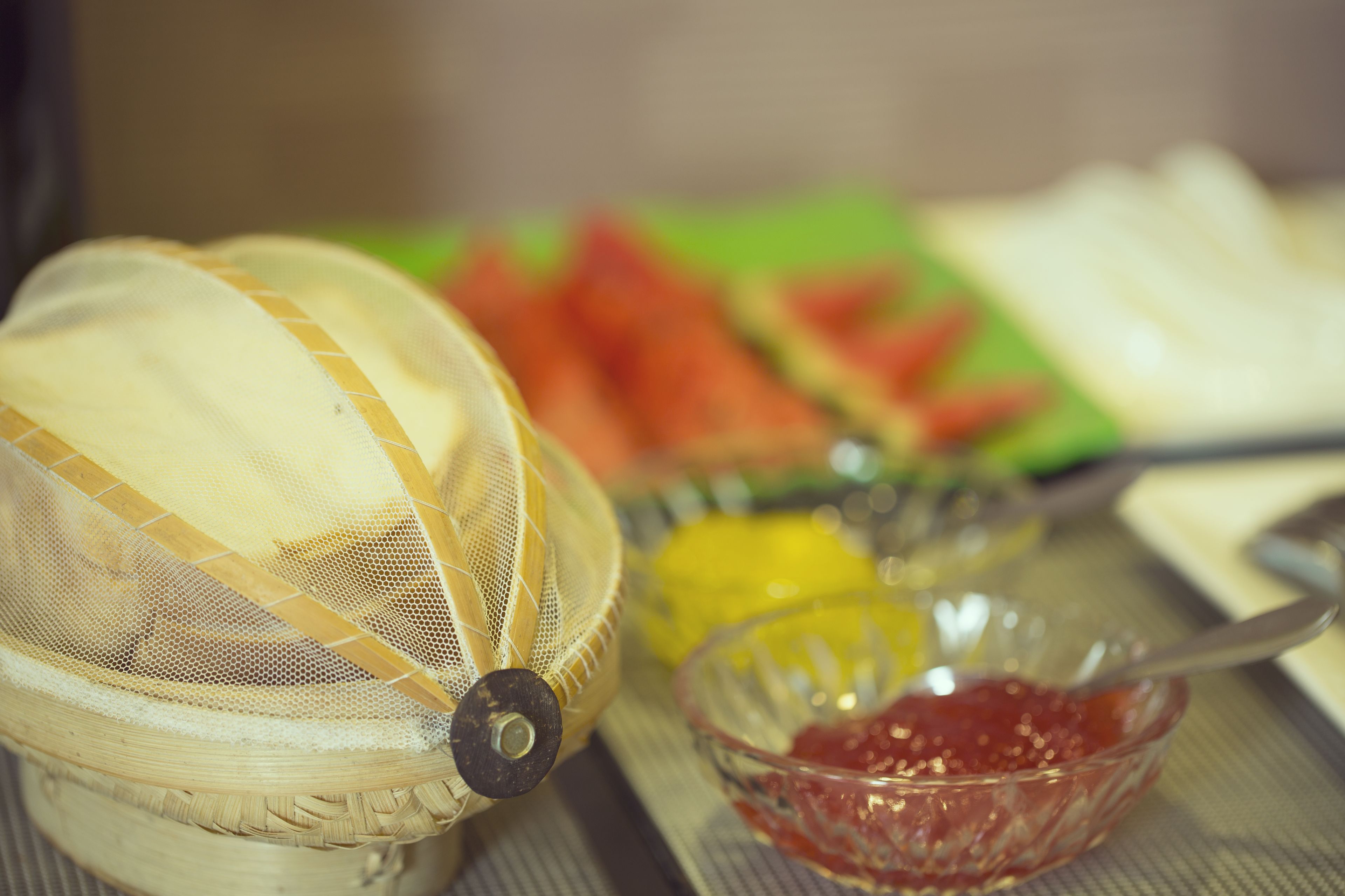 Una zona de preparación de alimentos con un colador, recipientes de condimentos y verduras en rodajas.