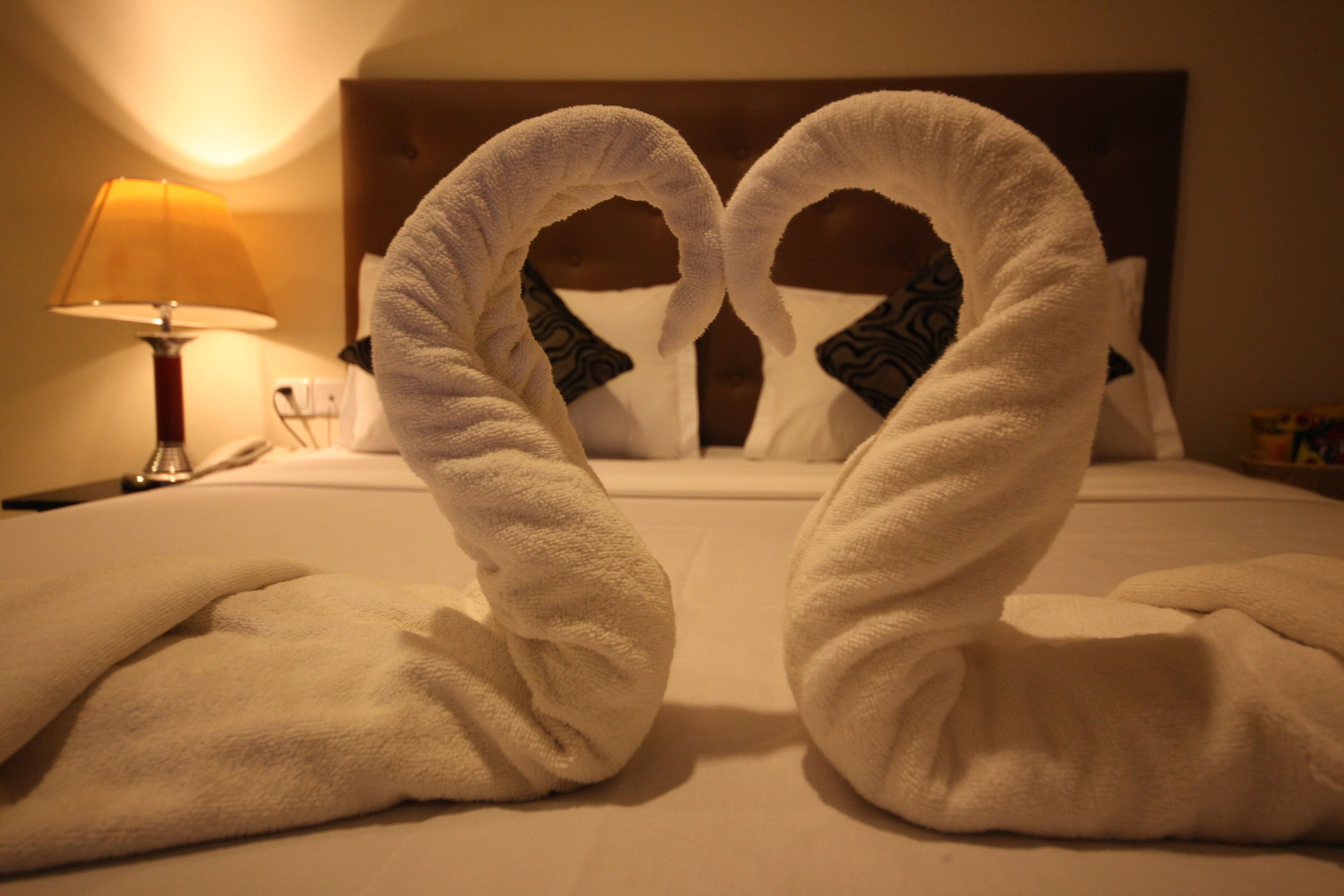Una cama con dos toallas dispuestas en forma de corazón.
