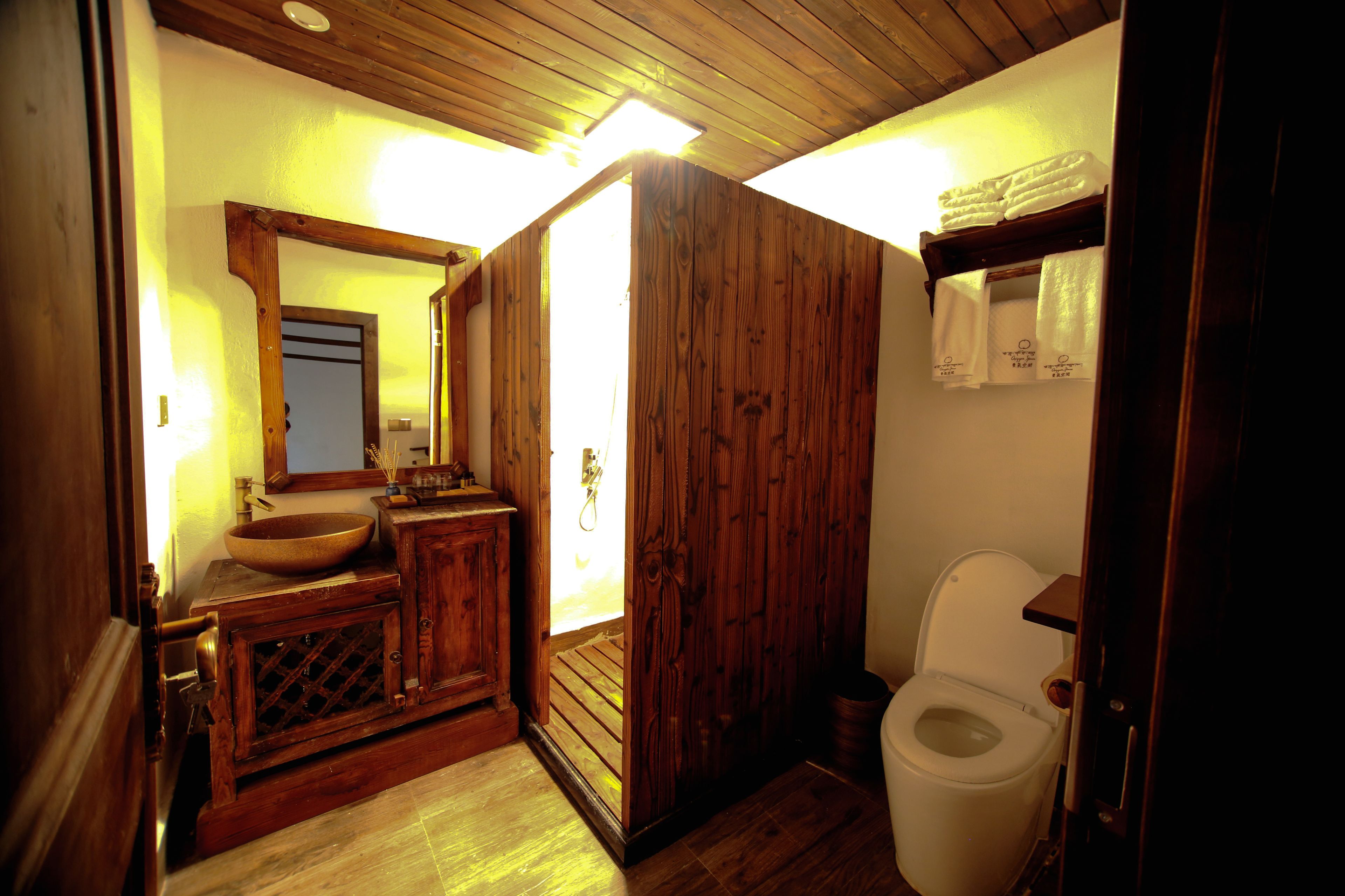 A wooden bathroom with a sink, mirror, and toilet.