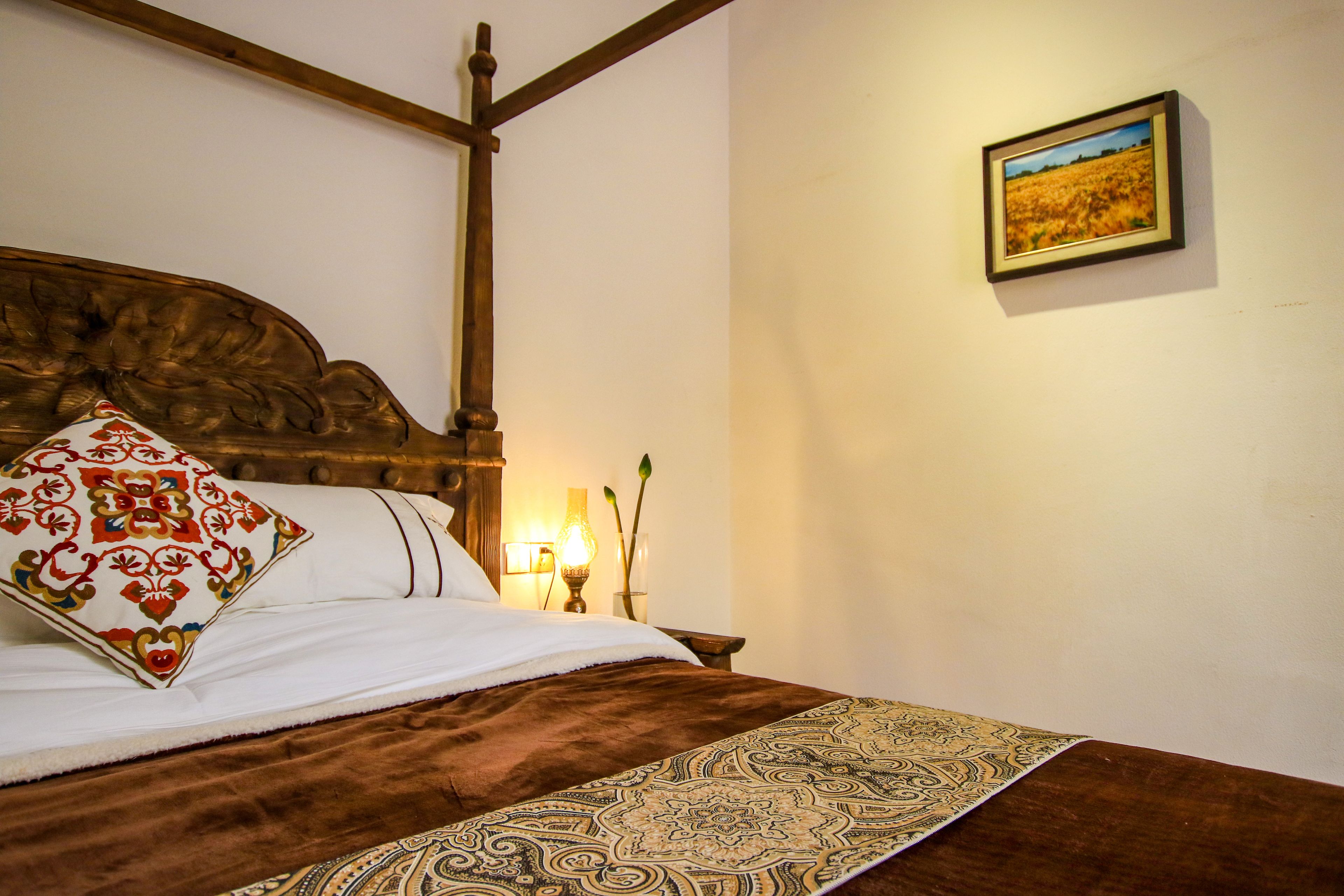 Un lit avec une tête de lit en bois, une couvre-lit à motifs et un coussin décoratif.