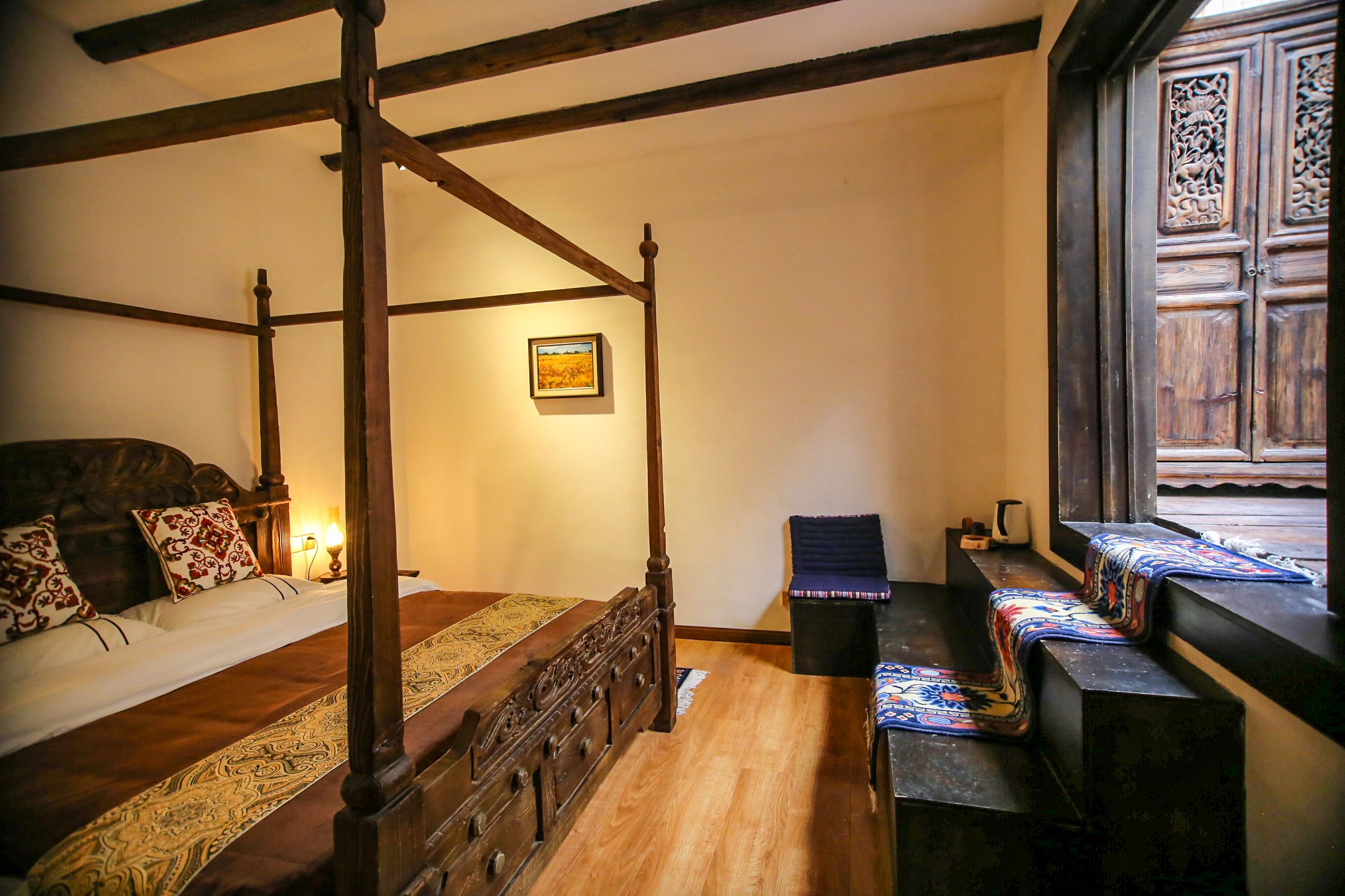 Uma cama de dossel tradicional com cabeceira de madeira, colcha estampada e uma moldura com imagem na parede.