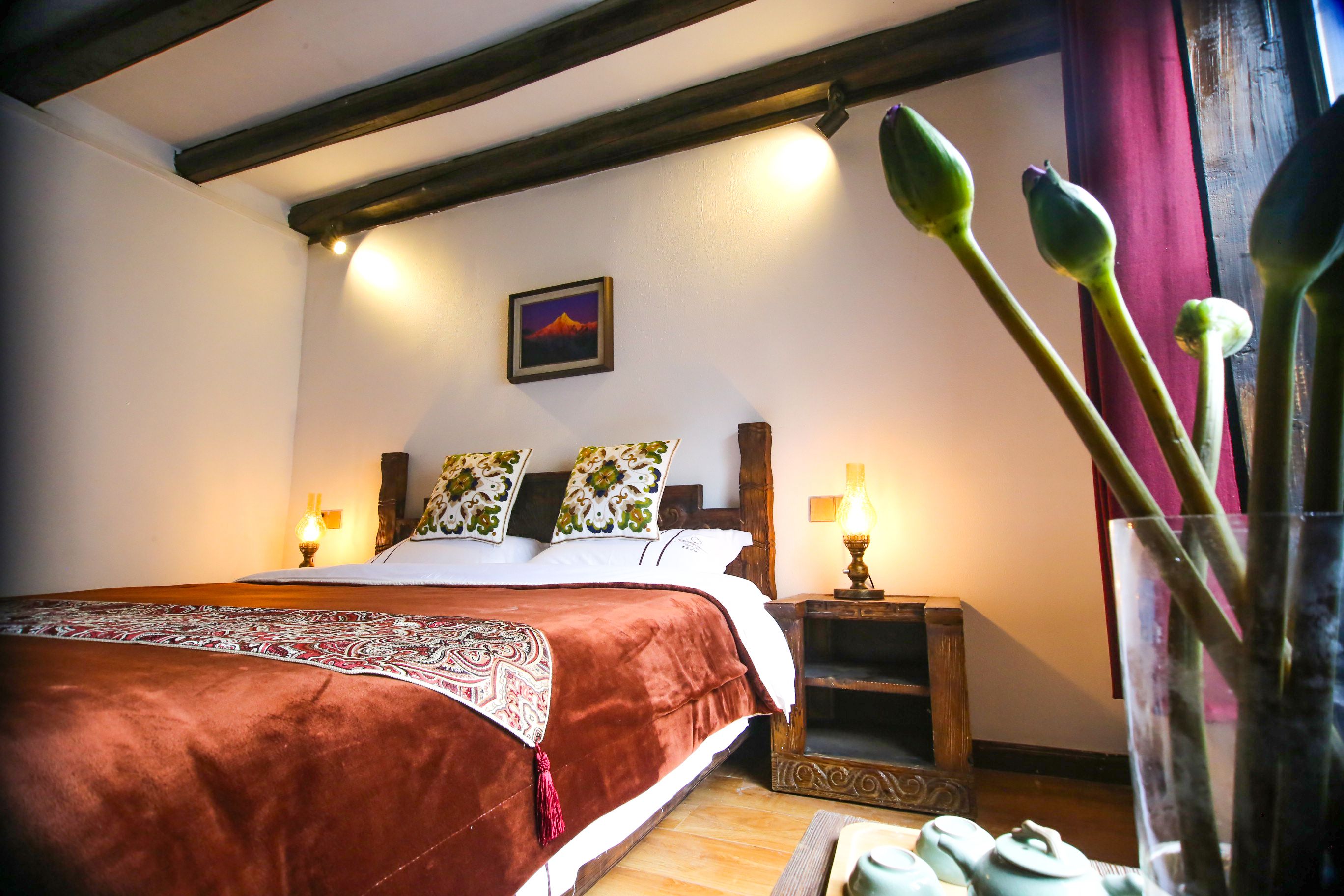 A bedroom with a large bed, wooden headboard, bedside lamps, and a framed picture on the wall.