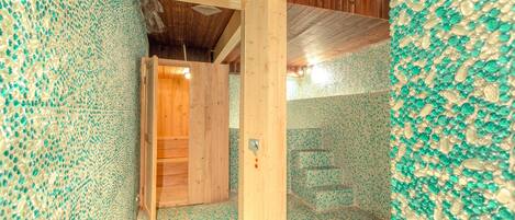 Una habitación con vigas de madera, una puerta de madera y paredes cubiertas de mosaicos.