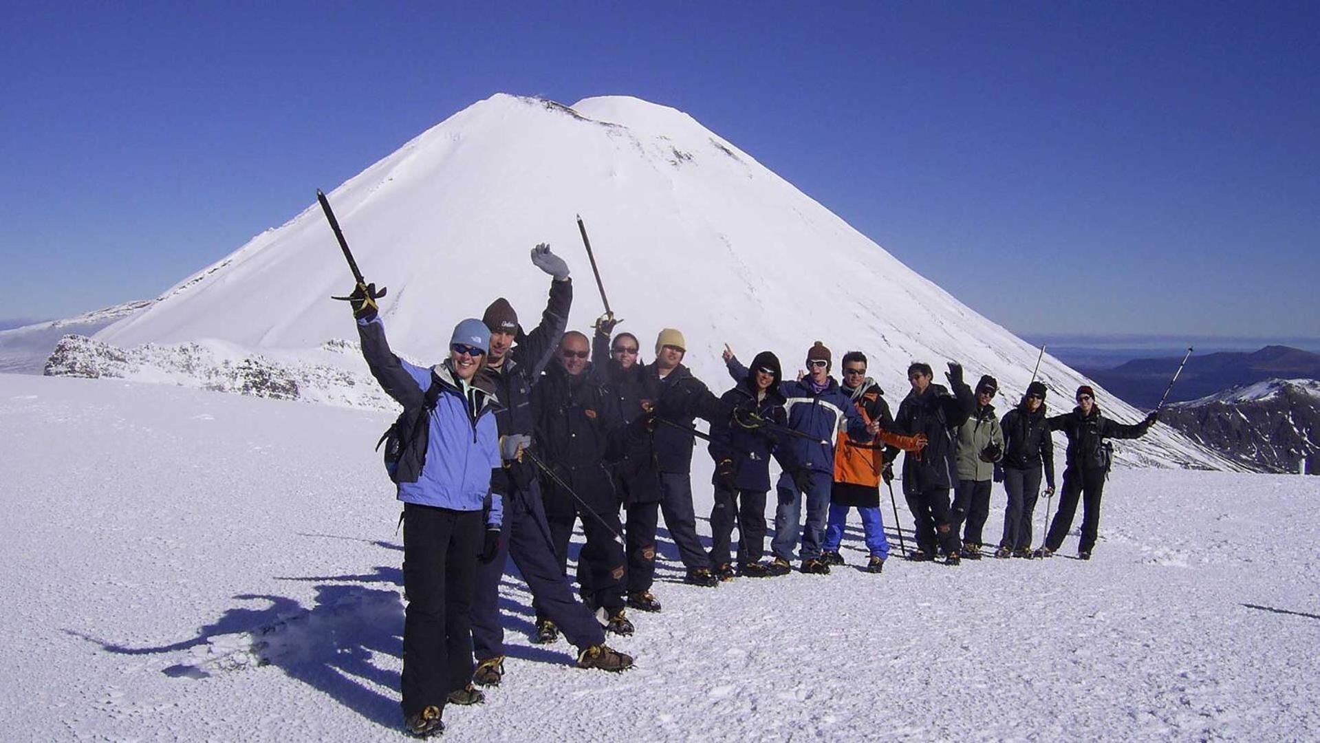 A group of people on a snowy mountain with a clear sky.