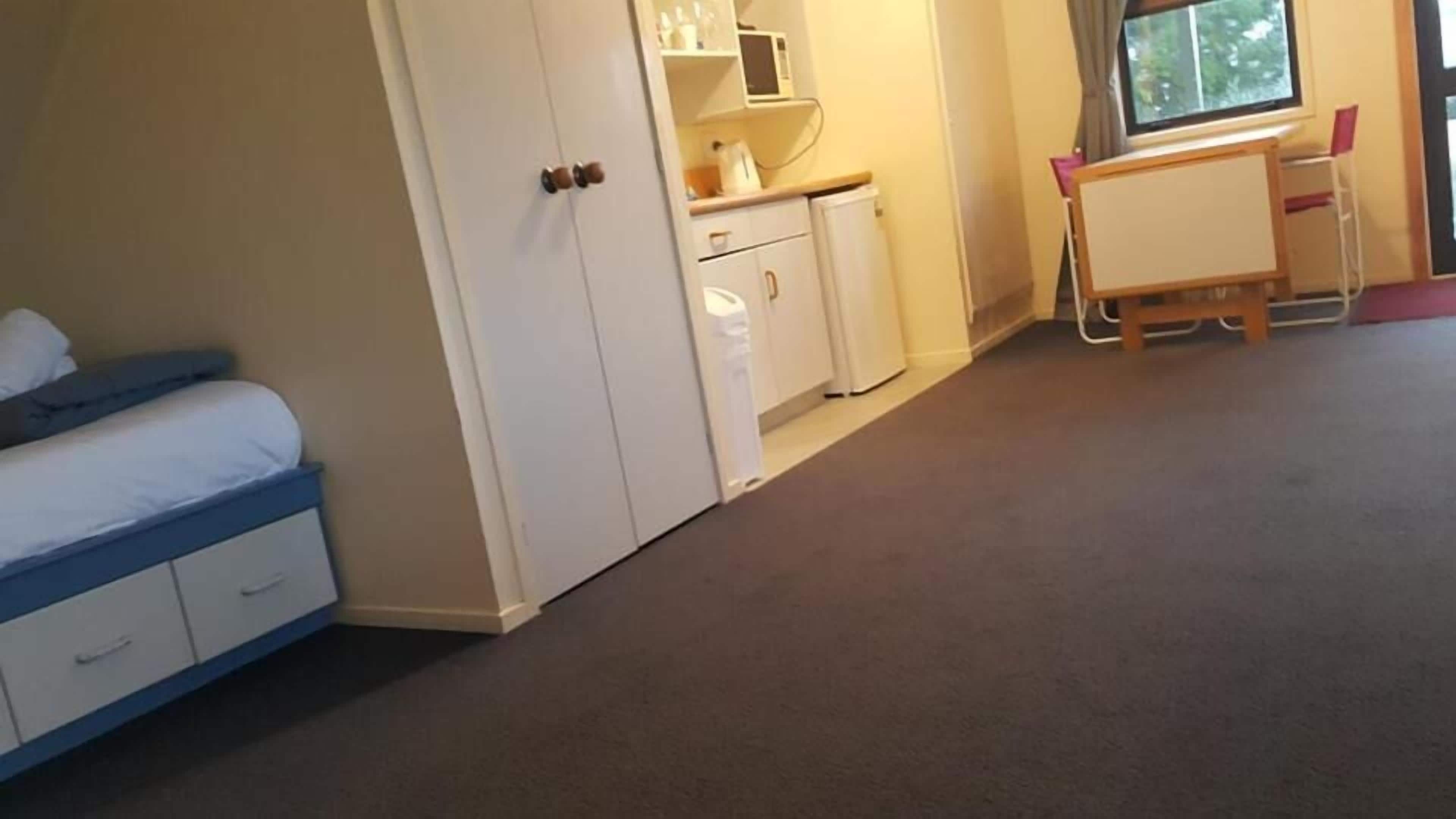 Ein Schlafzimmer mit Bett, Kleiderschrank, Schreibtisch und Stuhl sowie einem Fenster.