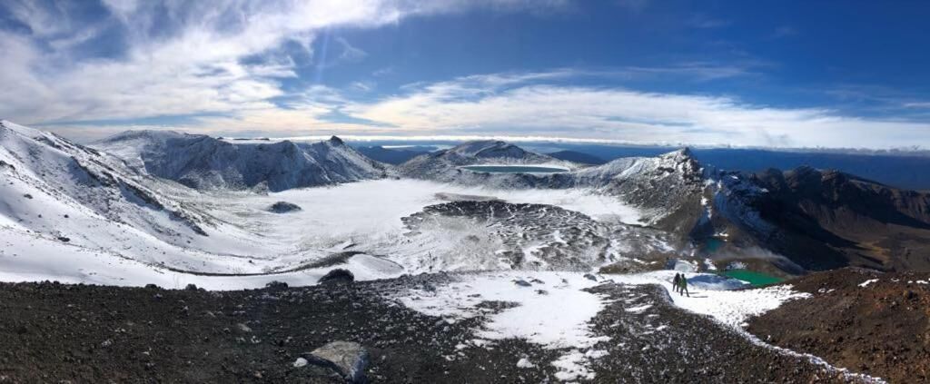 A panoramic view of a mountainous landscape with snow-covered peaks and a glacier.