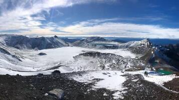 A panoramic view of a mountainous landscape with snow-covered peaks and a glacier.