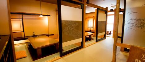 Una habitación japonesa tradicional con suelo de tatami, puertas correderas y una baja mesa con cojines.